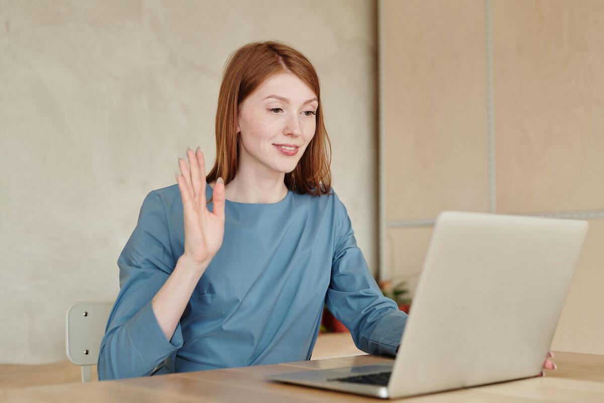 a woman waving at a laptop